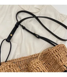 Detailed macro view of woven straw tote bag texture with black leather adjustable strap