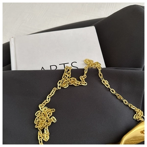 Detailed view of the luxury gold metal chain strap and creative hardware on straw bag