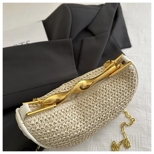 Detail of woven straw bag with wavy gold metal handle and luxury metallic chain strap
