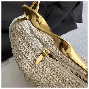 Detail of woven straw handbag featuring high-shine irregular gold metal handle and zipper