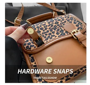 Detail showing the magnetic metal buckle and leopard print fabric on a retro messenger bag