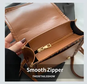Detail view of smooth gold zipper and leopard print trim on brown leather shoulder bag