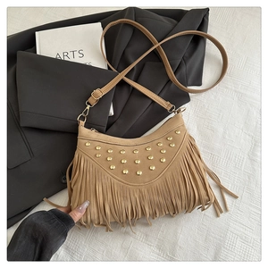 Detail of camel suede crossbody bag featuring golden rivets and long bohemian tassels