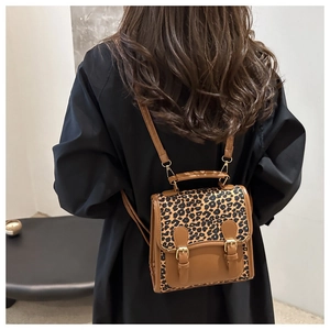 Detalle de mochila vintage de leopardo con solapa de cuero sintético y hebillas dobles