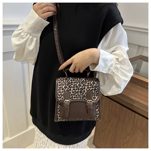Detail of trendy small backpack with leopard print flap and retro double buckle closures