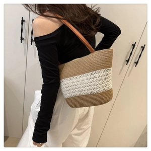 Detail of the woven straw bucket bag showing striped texture and brown leather strap