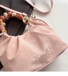 Close-up of pink drawstring handbag featuring marble-patterned beaded handle and logo