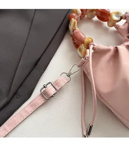 Detail of beaded handle and silver hardware on a dusty pink matte leather shoulder bag