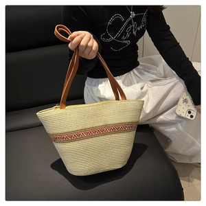 Detail der beige geflochtenen Tragetasche mit bunten Trägern und braunem Ledergriff