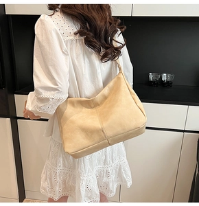 Close-up of beige soft leather tote bag showing textured surface and crossbody strap detail