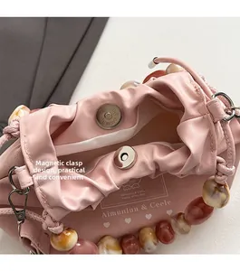 Detail of pink dumpling bag featuring magnetic closure and large amber resin bead handle