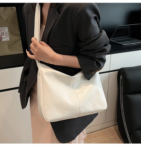 Close-up of white oversized hobo tote bag featuring a vertical stitched seam and wide strap