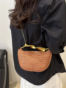 Minimalist straw handbag with gold twisted metal handle and fine chain shoulder strap