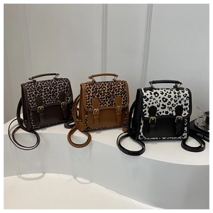 Detailed view of three leopard print backpacks on a display stand showing textures