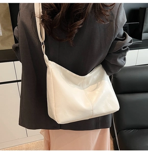 Detail of creamy white PU leather hobo bag with visible stitching and wide strap