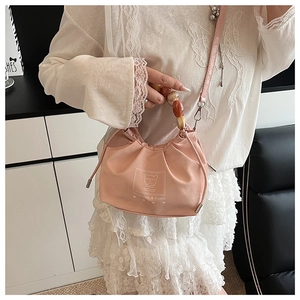 Pink pleated handbag with beaded handle and cartoon bear print shown on a model