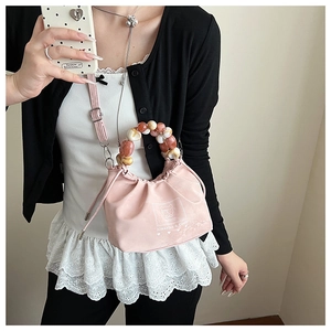Pink drawstring bucket bag featuring a marble acrylic bead handle and adjustable strap