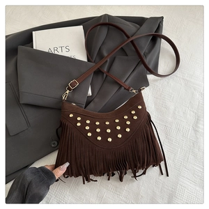 Detailed macro of dark brown suede bag with gold studs and bohemian tassel accents