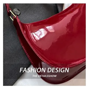 Detail of wine red patent leather shoulder bag with glossy finish and gold metal buckle