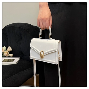 Close-up of the elegant white leather crossbody bag with a gold oval metal lock closure