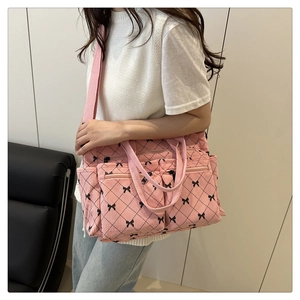 Detail of pink corduroy tote bag with black bows and spacious double front zipper pockets