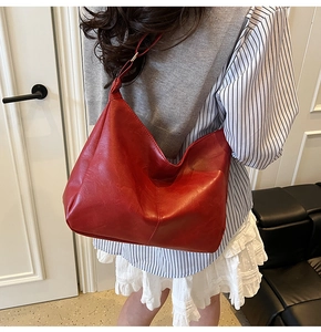 Detail of red oversized leather tote bag with vertical stitching shown on model shoulder