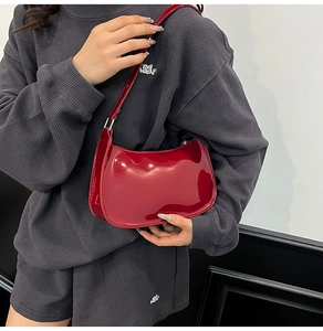 Detailed view of glossy red patent leather underarm bag worn by model on shoulder
