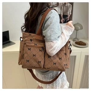 Detail of brown corduroy tote bag with bow patterns and double front zipper pockets