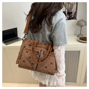 Brown corduroy tote bag with bow patterns and double zip pockets on a casual model