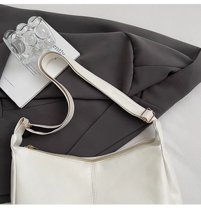 Close-up of cream hobo tote bag featuring fine texture and adjustable strap with gold buckles