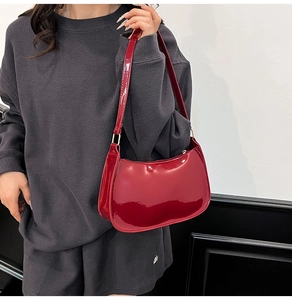 Detail of red glossy crescent shoulder bag with golden hardware and zipper closure