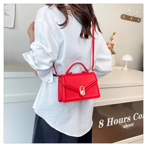 Macro detail of red crossbody bag with golden metal swivel lock and smooth matte finish