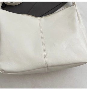 Detail of white lychee-textured leather tote bag with vertical double-stitching and zipper