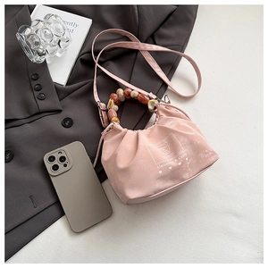 Close-up of pink pleated fabric handbag with amber beaded handle and long shoulder strap