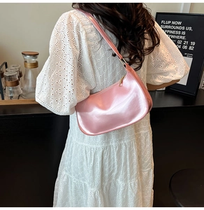 Detail of glossy pink patent leather hobo bag with gold zipper and mirror finish surface