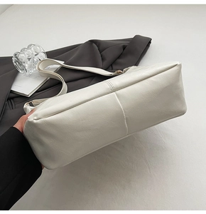 Detailed view of cream PU leather tote bag with reinforced cross-stitching on the bottom