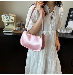Close-up of pink glossy leather underarm bag with gold zipper in a cafe setting
