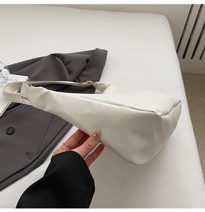 Close-up of white leather Hobo bag with gold buckle on gray suit background