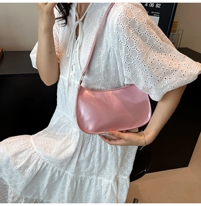 Close-up of pink glossy patent leather hobo bag worn with white lace dress