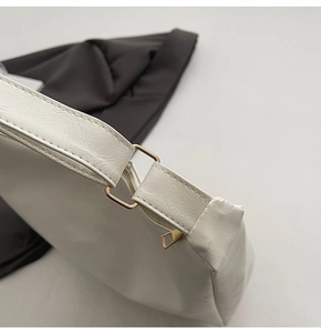 Detail of light gold D-ring hardware and fine stitching on a cream leather tote bag