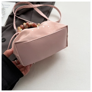 Pink satin handbag with amber resin bead handle and white heart print details