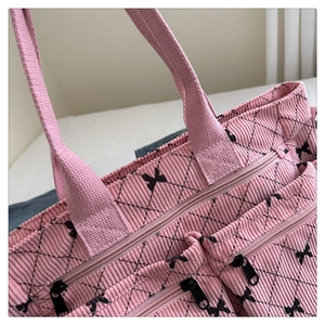 Dettaglio della borsa tote in velluto rosa con motivi a fiocco e cuciture trapuntate