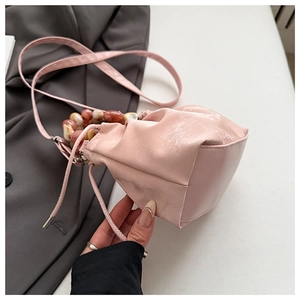 Detail view of pink pleated bucket bag with marble bead handle and soft drawstring closure