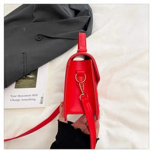 Detail view of the red leather shoulder bag side with elegant gold metal ring buckle