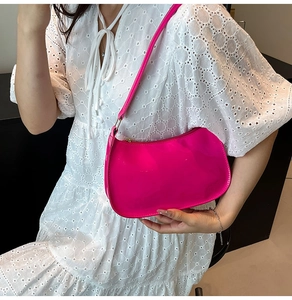 Detail of bright pink patent leather underarm bag with glossy finish and gold zipper