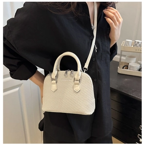 Detail of a beige woven texture handbag with double handles and slim shoulder strap