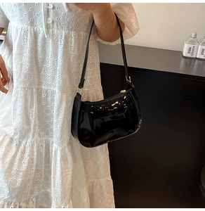 Close-up of black glossy patent leather hobo bag with a sleek metal zipper detail