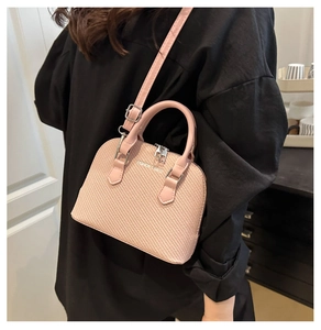 Pink shell handbag with woven texture and silver hardware shown on a model