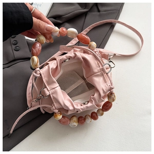Detail of pink pleated bucket bag with amber resin bead handle and magnetic snap closure