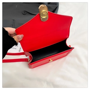 Detail view of red faux leather crossbody bag with oval gold twist lock and black lining